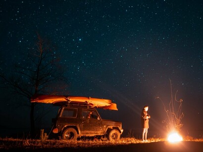 A man standing quietly beside a bonfire in the open sands, highlighting the solitude and scale of the Sahara