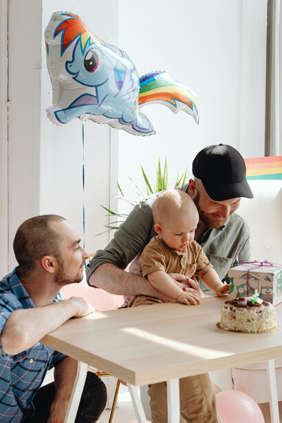 A same-sex couple enjoying playtime with their child, capturing the spirit of queer family and imagination