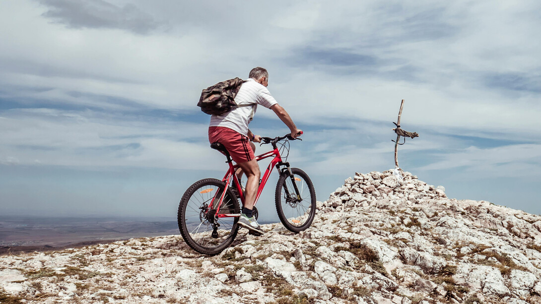 Homem se desafia a pedalar em cima de montanha. Entenda a importância de se propor novos desafios em cada fase da vida