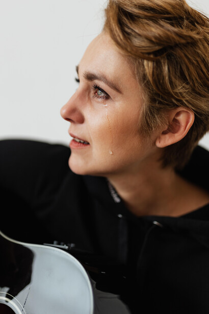 A woman cries while playing the guitar