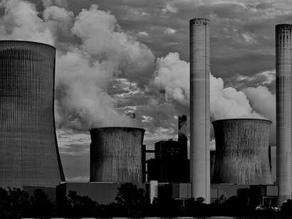 Grayscale photo of smokestacks releasing carbon emissions, illustrating fossil fuel pollution and the impact of burning coal and oil