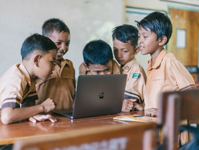 Young students busy learning together, in a team, with a laptop, in a classroom
