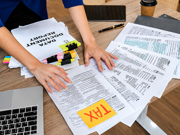 Accountant reviewing and organizing tax documents and financial reports at a desk