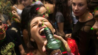 Young woman drinking alcohol from a bottle at a party