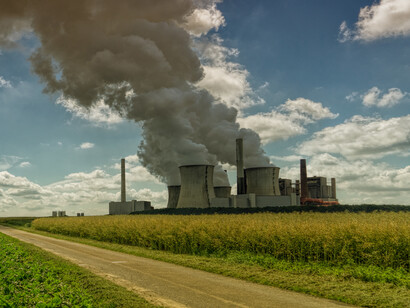 A power plant fuming vapors besides a dirt road