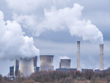 White smoke escapes from the stacks of the nuclear facilities, creating a striking contrast against the sky
