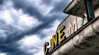 Abandoned movie theater standing silent beneath a stormy sky, evoking nostalgia, decay, and the fading echoes of a once-vibrant past