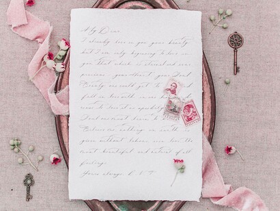 A love letter handwritten and displayed with its stamps and petals from flowers