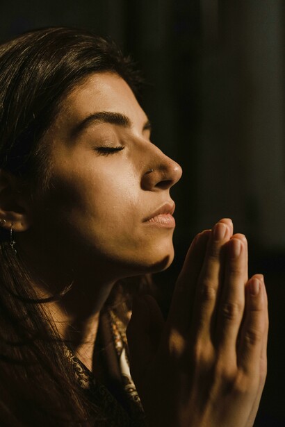 Mujer cierra los ojos al orar. Orar no es pedir y pedir, sino pedir y cambiar