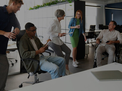 A wheelchair user actively contributing at his office job, collaborating with a diverse team, showcasing inclusivity in the workplace