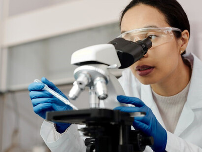 A woman carefully examining samples under a high-powered microscope, delving into the intricacies of molecular biology, while exploring the cutting-edge realms of gene therapy and advanced cell-based treatments