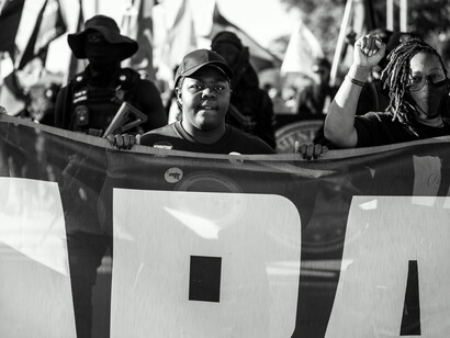 A group of African demonstrators standing united behind a banner with raised fists, symbolizing resistance against oppression and inequality