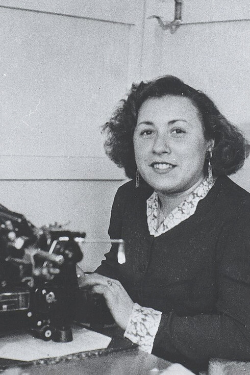 Secretaria posa para la fotografía mientras trabaja en una máquina de escribir