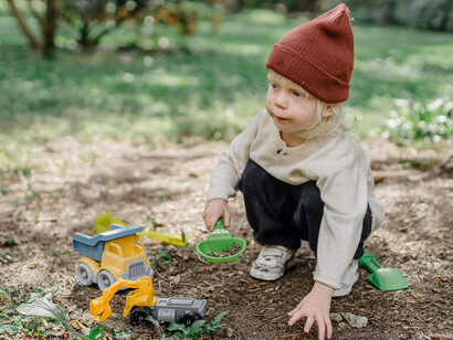 In the backyard, a little boy digs with a plastic shovel, searching for a hidden treasure buried in the soil