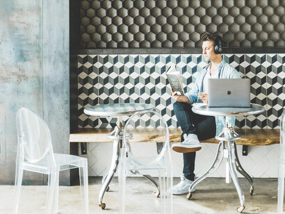 A man sits in a lively café, working intently on his laptop
