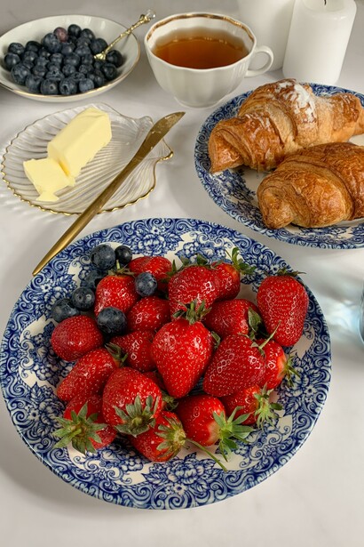 A plate of strawberries and blueberries with croissants and tea