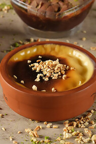 Indulge in delectable rice pudding served in a traditional clay bowl, adorned with crunchy hazelnut pieces