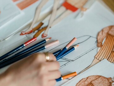 Mão segurando um lápis sobre uma mesa. O processo criativo revela que grandes ideias começam com um simples traço