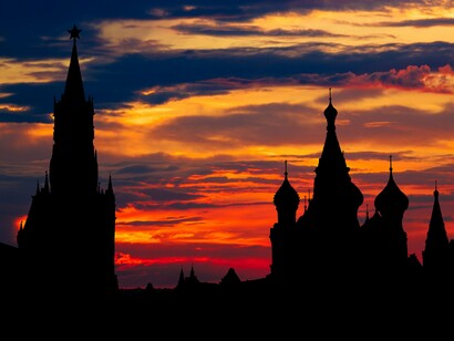 The silhouette of the Kremlin against a fiery sunset, reflecting the power of the Russian state through changing eras