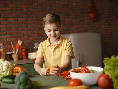 A boy cooking a nutritious vegetable curry in the kitchen, featuring broccoli, to support the Zero Hunger Initiative
