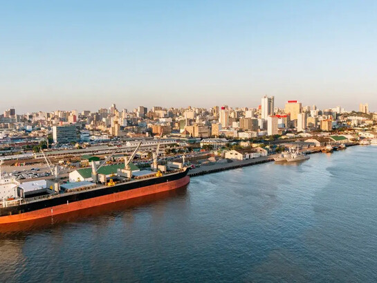 Vista panorâmica do porto de Maputo, com o horizonte urbano e as águas da baía em destaque. A dinâmica econômica moçambicana exige que as empresas adotem métodos quantitativos para controlar custos e tomar decisões mais precisas em ambientes de constante transformação