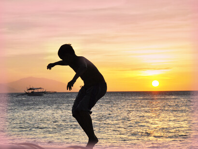 A man does a pose near the sea in the sunshine