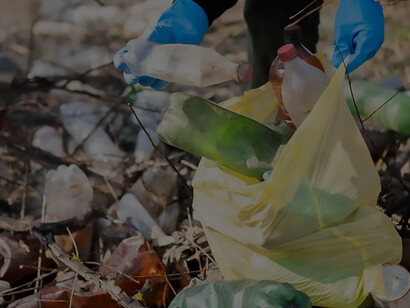 A man conscientiously gathers stray plastic bottles from the ground, engaging in recycling to combat pollution