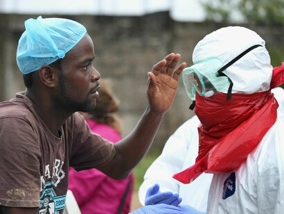 Un joven africano acaricia a uno de los voluntarios llegados a su país para combatir el ébola