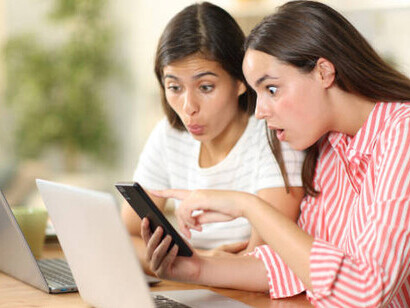 Two girls gaze at the screen in disbelief, stunned by the memes they’re seeing online