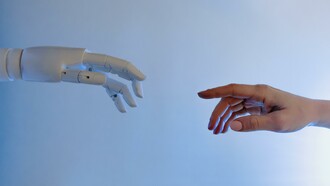 Mão de robô representando a inteligência artificial e mão de um humano