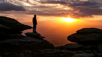 La sagoma di un uomo che si affaccia su un paesaggio al tramonto