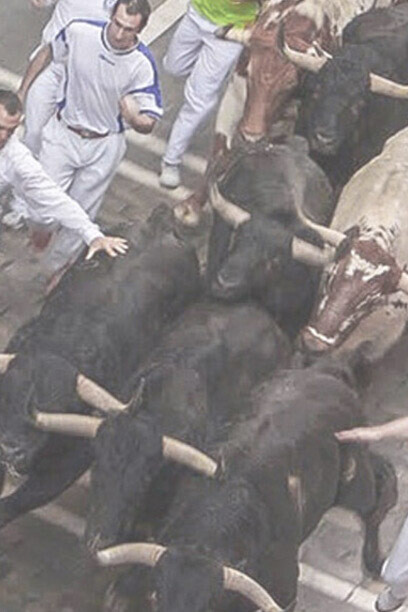 Los corredores se enfrentan a los toros en la calle Estafeta, Pamplona, Navarra, España