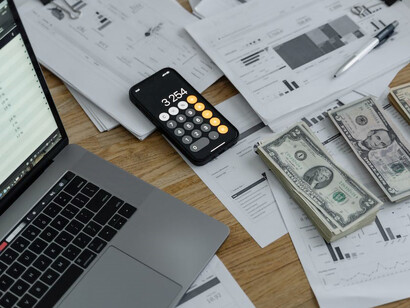 Papers, a calculator, coins, and investment instruments are neatly arranged on a table
