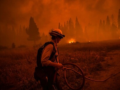 Stephanie Lockhart, 28, from the North Lake Tahoe Fire District, works to protect homes and shelters as the Caldor fire rips through the canyon near the Sierra Nevada mountain range at a Lake Tahoe lodge along Highway 50, in California, August 29, 2021 captured by Lynsey Addario
