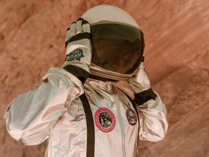 Astronauta percorre uma região árida durante atividade de exploração. A paisagem rochosa sugere um ambiente semelhante ao de outros corpos celestes. Missões espaciais e observações astronômicas ajudam a ampliar o conhecimento sobre o cosmos e seus mistérios. Enquanto os OVNIs despertam curiosidade, a ciência segue investigando evidências concretas sobre vida fora da Terra