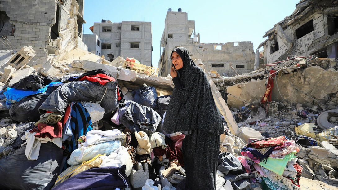 A woman navigates the ruins of her former home, a poignant image of resilience amid widespread destruction during war