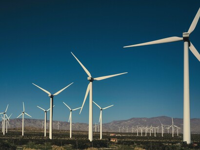 Um parque eólico se estende pela paisagem, com suas turbinas distribuídas pelo horizonte. A expansão dessa infraestrutura representa uma das estratégias utilizadas para ampliar a participação de fontes renováveis na matriz energética