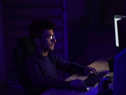 A man in a black long-sleeve shirt is using a computer