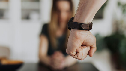 A clenched fist of a person wearing a leather wristwatch, symbolizing domestic violence, fear, and trauma