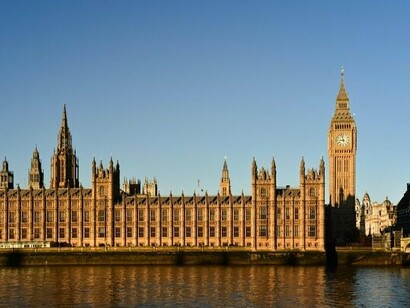 The Palace of Westminster in London, England, stands beside the River Thames, representing the foundation of parliamentary democracy