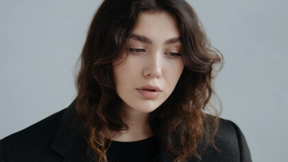 Modelo com pouca maquiagem e blazer preto mais folgado dando liberdade e conforto ao seu corpo