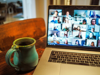 A laptop computer placed on a brown wooden table symbolizes an online community, fostering virtual interaction, social connection, and digital communication