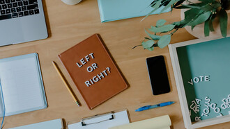 On the desk, Left or right? written on a notebook emphasizes the importance of voting