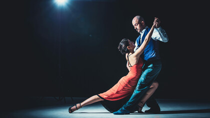 A couple tangoing beneath the spotlight