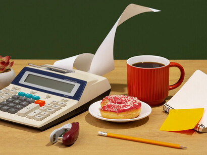 Calculator on a desk with a donut and coffee, illustrating food cost calculation and ingredient pricing for cafés