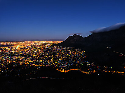 Cape Town's urban landscape, featuring iconic landmarks such as Robben Island and Lion's Head illuminated at night, offers a captivating glimpse into South Africa's urbanization