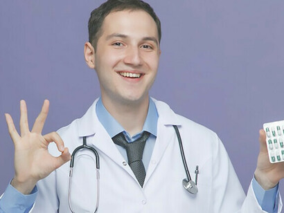 Un joven médico, adornado con traje médico y estetoscopio alrededor del cuello, sonríe mientras sostiene la medicación en la mano