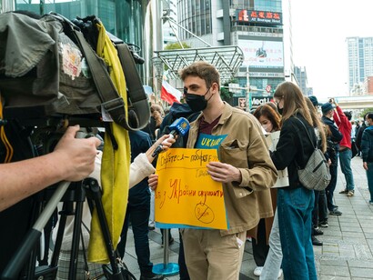 Ukrainian national visiting Hong Kong is being interviewed for television and is holding a sign wishing for peace in Ukraine