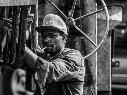 With weary eyes and a moment of respite, he embodies the tireless effort of those labouring in challenging conditions, reflecting the unseen struggles of daily life in poverty