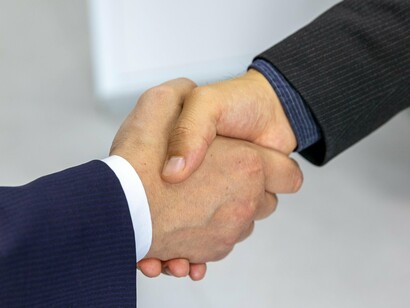 Duas pessoas apertam as mãos durante uma reunião profissional, em um gesto associado a acordo e compromisso. A formalização de relações entre diferentes atores é parte da dinâmica necessária para transformar recursos e decisões em projetos concretos